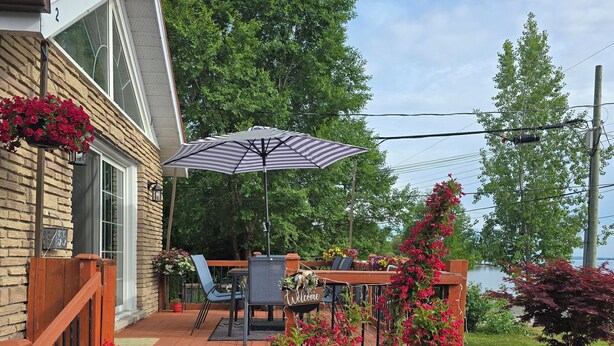 A wooden deck with a patio table and chairs, a welcome sign, and potted plants. - Lakeview, Warm and Inviting, Family Home (Keswick)