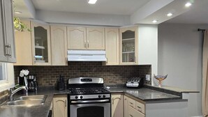 A modern kitchen with dark wood flooring, stainless steel appliances, and light wood cabinetry. - Lakeview, Warm and Inviting, Family Home (Keswick)