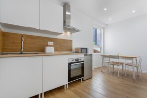 Eine moderne Küche mit weißen Schränken, einer Holz Arbeitsplatte, einem eingebauten Ofen und einem Essbereich mit Tisch und Stühlen.