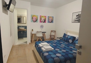 Ein Schlafzimmer mit einem Bett, einem Schreibtisch, einem Stuhl, einem Spiegel und Bildern an der Wand.