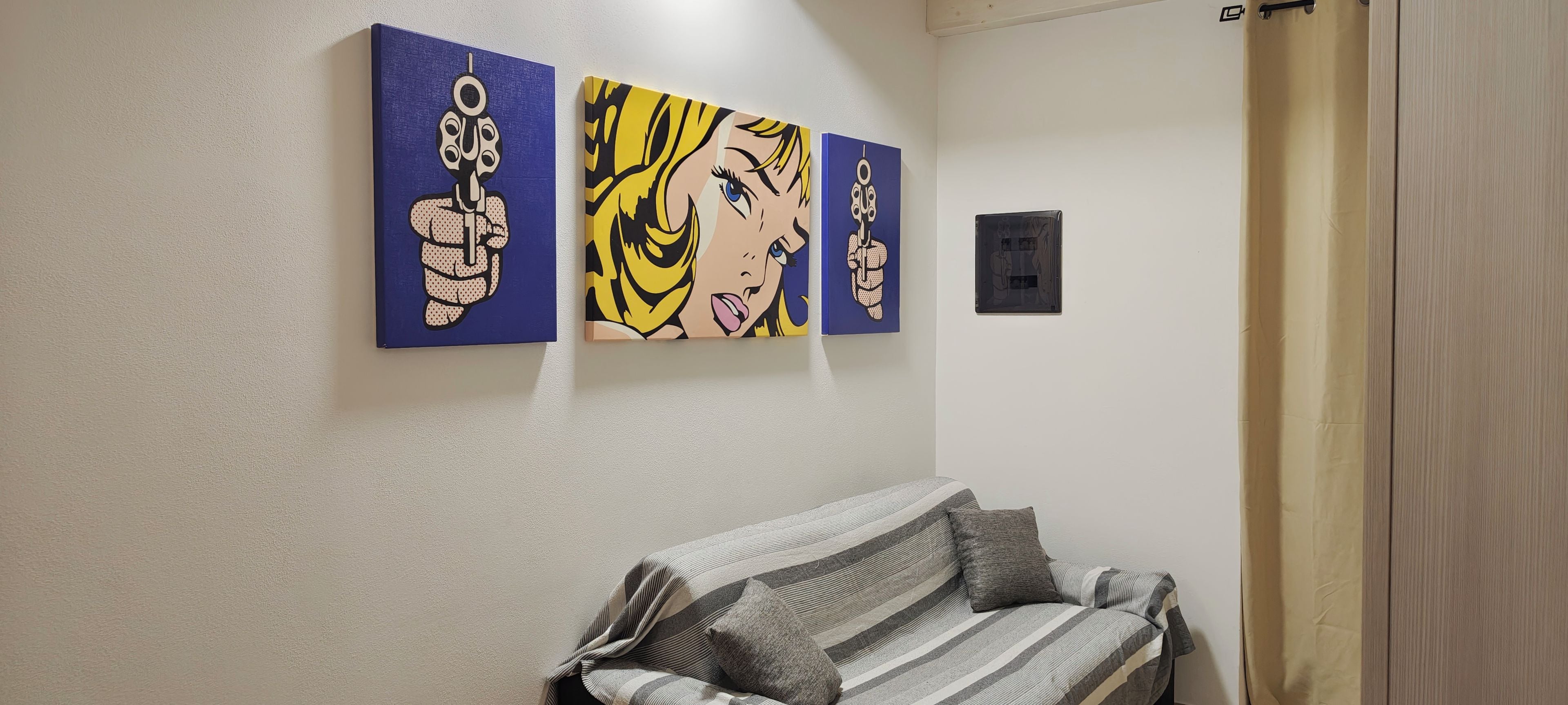 A room with a sofa and three wall-mounted artworks.