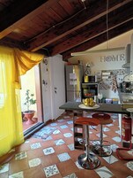 Una cocina con piso de baldosas, un refrigerador, un microondas y un lavaplatos.