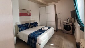 A bedroom with a bed, a washing machine, a TV, and a wardrobe. - Archubintu B&B (Sassari)