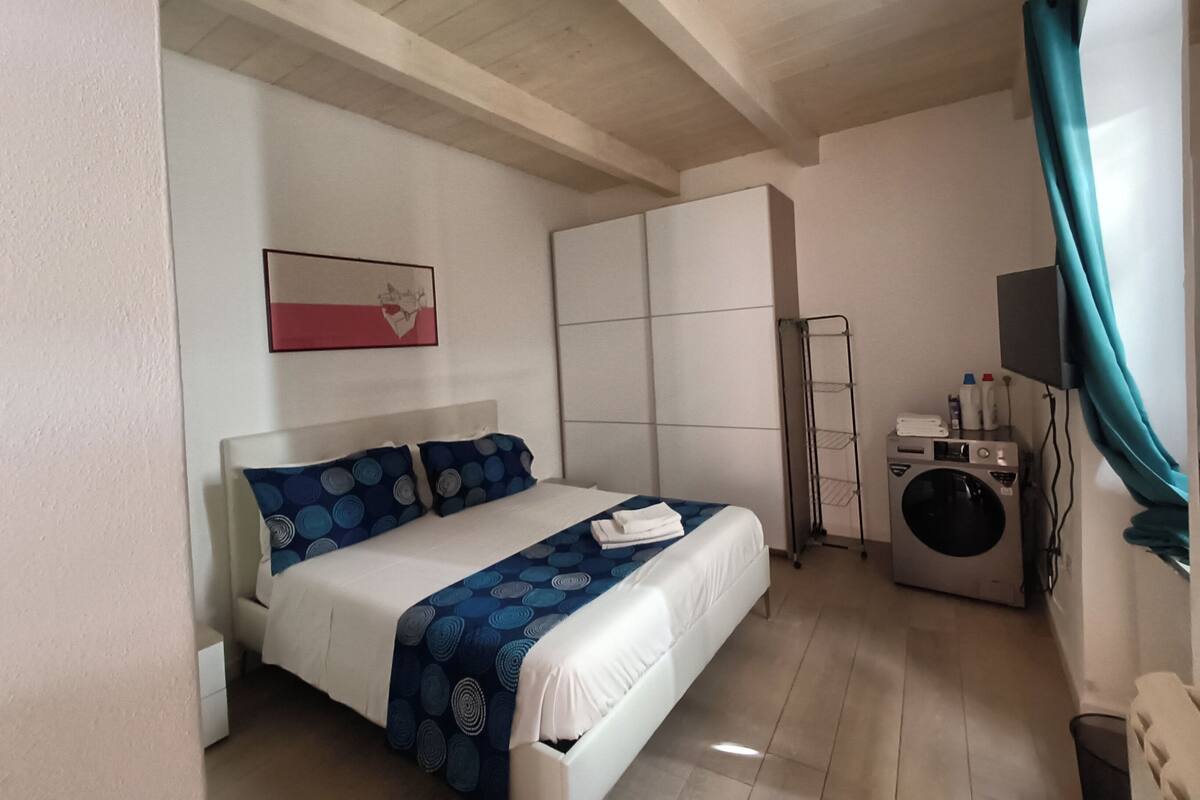 Un dormitorio con cama, lavadora, televisor y armario.