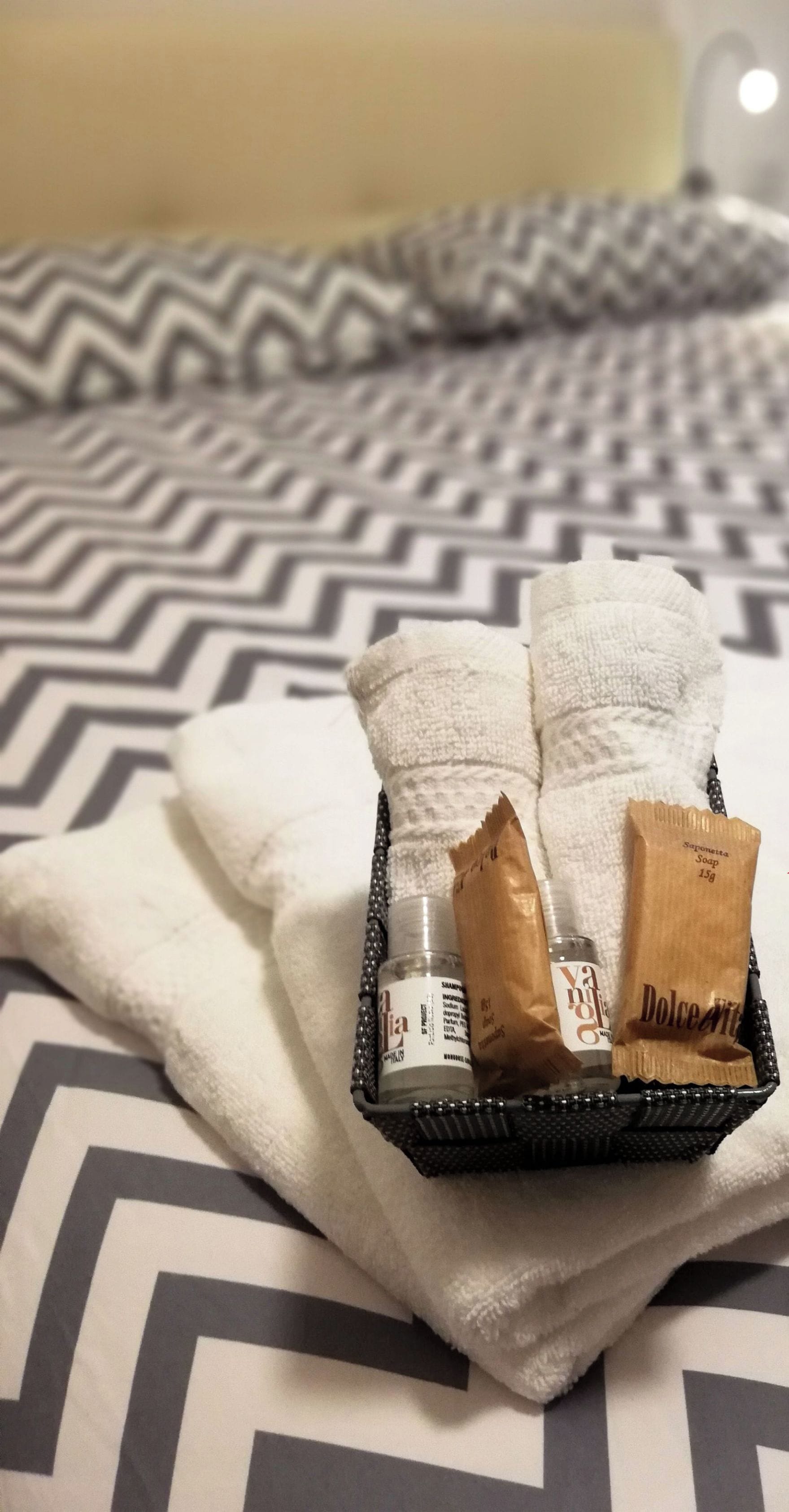 Een netjes opgeruimde badkamer met een zwart-wit gestreept handdoek, een klein zwart dienblad met toiletartikelen, en een logo voor 'archubintu b&b sassari'.