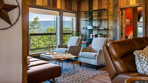 A cozy room with a large window, wooden walls, and leather furniture.