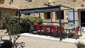 A stone building with a covered outdoor seating area, a barbecue grill, and a gravel patio. - Gite for 15p at the foot of Mont Ventoux_Lacets du Ventoux (Beaumont-du-Ventoux)