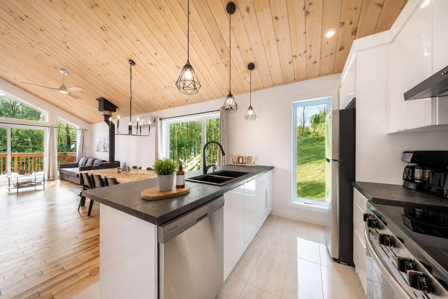 A modern kitchen with a central island, large windows, and a dining area with a view.