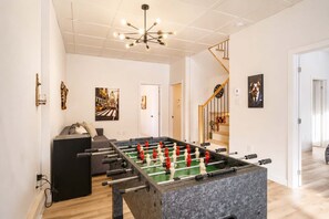 Un salon moderne avec une table de baby-foot, un canapé et un escalier.