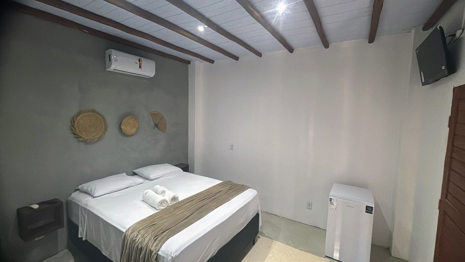 Een slaapkamer met een bed, nachtkastje, wandairconditioner en een kleine verwarming.