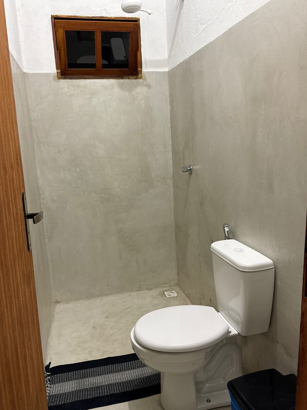A small, enclosed shower area with a toilet and a window.