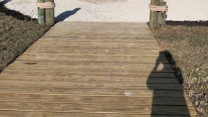 A wooden pathway leading to a white building with multiple balconies and a gated entrance. - IT'S A SHORE THING - 
ON THE BEACH - SPECTACULAR SUNSETS
NEWLY RENOVATED (Fort Myers Beach)