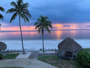 A beach view with palm trees, a wooden deck, and thatched-roof structures. - SPECTACULAR SUNSETS ON THE BEACH
SAND SCULPTING CHAMPIONSHIP NOV. 19-23 (Fort Myers Beach)