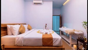 Una habitación de hotel con una cama, una camilla de masaje y una mesita con velas.