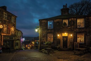 A historic building with a sign reading 'Black Bull,' featuring a traditional pub atmosphere with outdoor seating and a brick facade. - Heathcliff Cottage (Keighley)