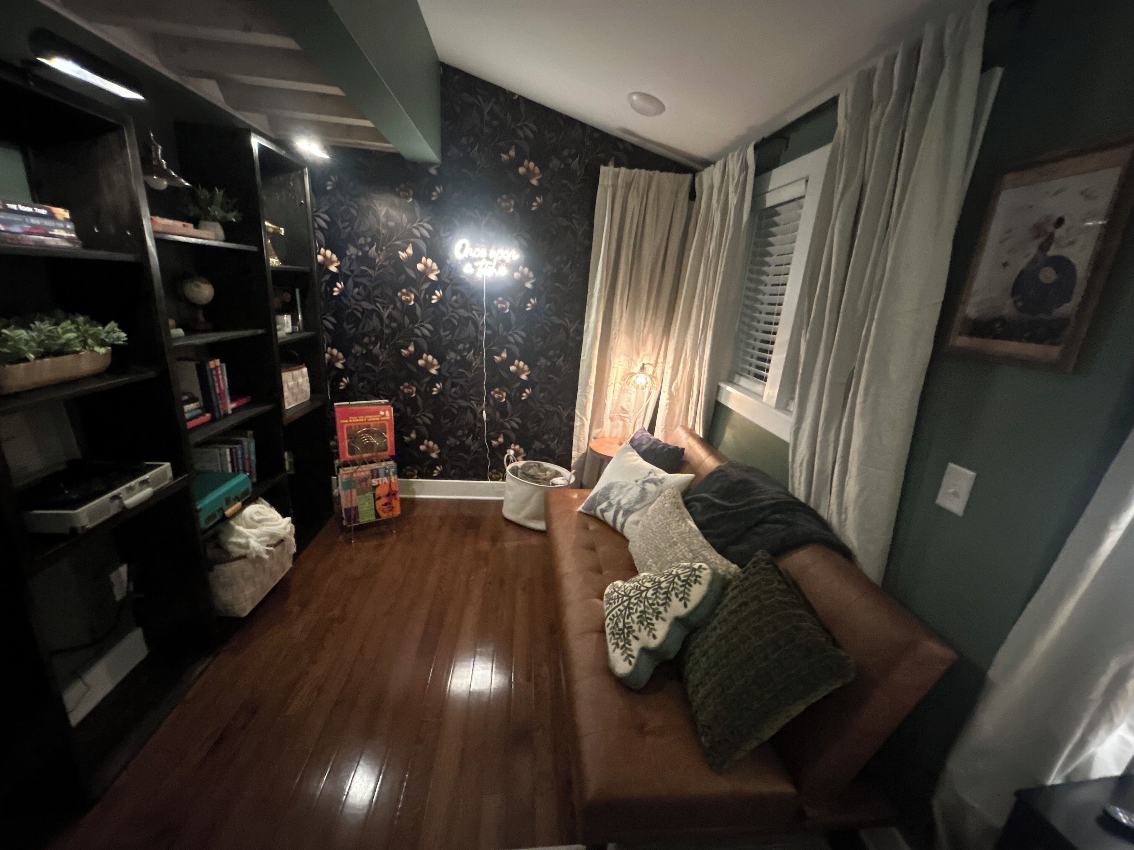 Una sala de estar acogedora con un sofá, una estantería y una lámpara.