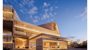 Un edificio moderno con un diseño arquitectónico único, que presenta un techo inclinado y una serie de elementos verticales de madera.