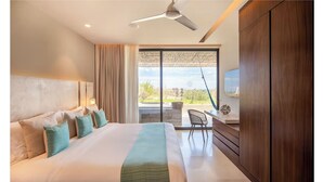 Una habitación de hotel moderna con una cama grande, un ventilador de techo, un televisor y vistas al exterior.
