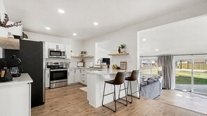 A modern kitchen with white cabinets, stainless steel appliances, and a central island with bar stools.