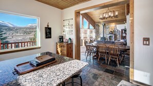 Une cuisine dotée d’un plan de travail en granit, de meubles en bois et d’un coin repas avec un mur en pierre et des chaises en bois.