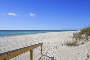 A sandy beach with a wooden railing and a clear blue sky. - A Summer Lovin (Destin)