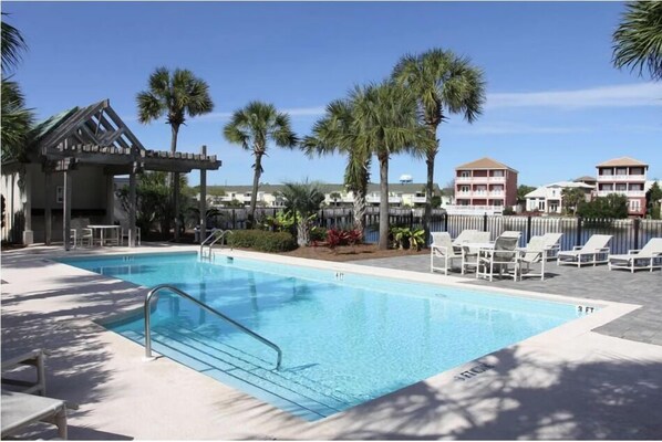 A swimming pool with lounge chairs and palm trees. - A Summer Lovin (Destin)