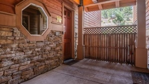 A wooden cabin with a stone foundation, a wooden door, and a lattice fence. - Walk to Village, Gondola, Shops + Free Shuttle! (Mammoth Lakes)
