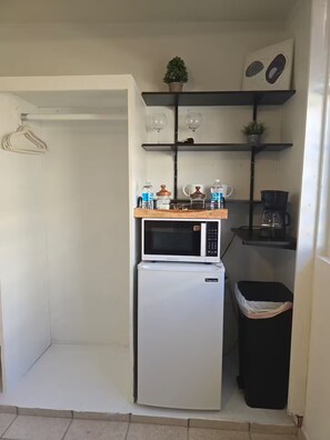 A compact kitchen with a microwave and refrigerator, a coffee maker, and a trash bin. - Mil Campanas Apt 3 / Camellia House (Aguadilla Pueblo)