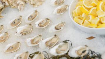 A display of oysters on ice with lemon wedges and seaweed.