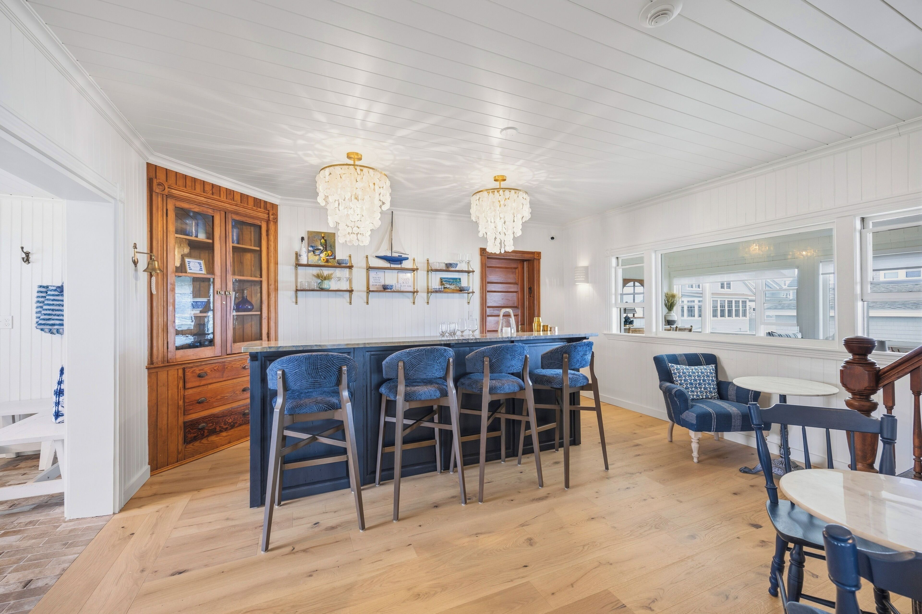 Une cuisine avec des meubles en bois, un coin bar avec des chaises bleues et un espace repas avec une table et des chaises.