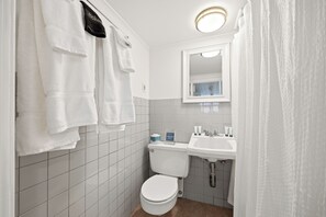 Un baño con inodoro, lavamanos y toallas.
