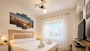 Ein Hotelzimmer mit Bett, Nachttischen, Fernseher und Bildern an der Wand.