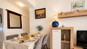 Ein Essbereich mit einem für das Frühstück gedeckten Tisch, einem Fernseher und einem dekorativen Regal.