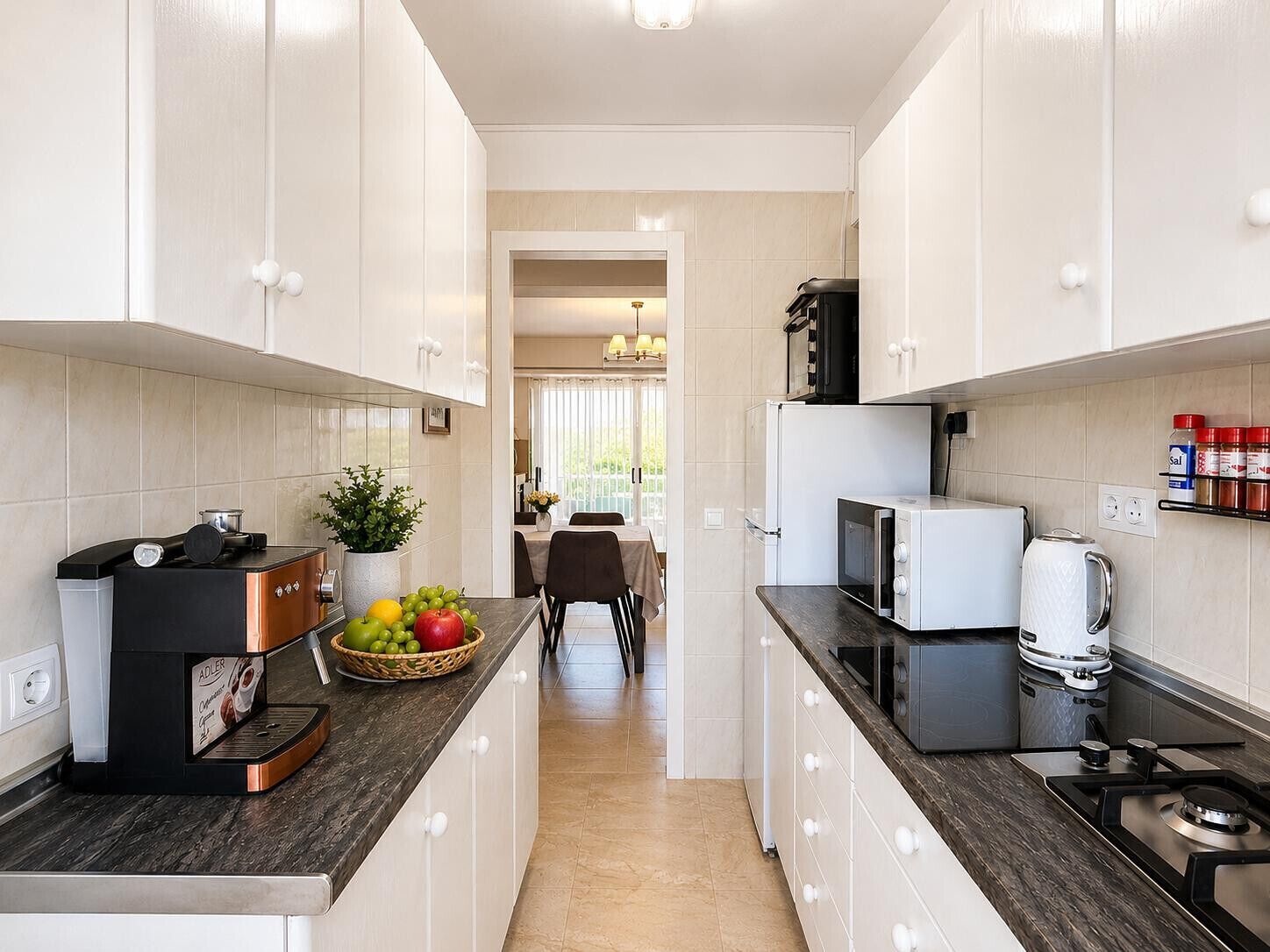 A modern kitchen with white cabinets, a coffee machine, a microwave, and a gas stove.