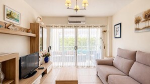 Ein Wohnzimmer mit Fernseher, Sofa und einem Balkon mit Blick.