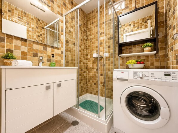 A modern bathroom with a glass shower enclosure, a built-in washing machine, and a tiled backsplash. - SUNNY GEMINIS (Calpe)