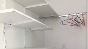 A room with white walls, a black cabinet, and a clothes rack with various hangers. - Suítes da Lagoa do Peri (Florianópolis)