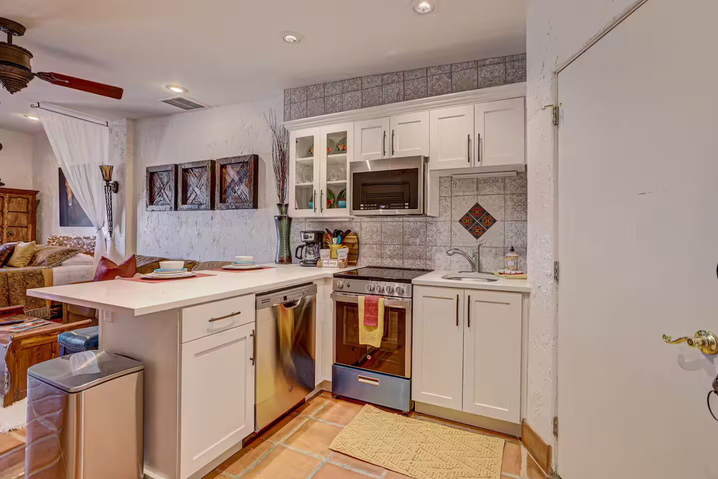 A compact kitchen with white cabinets, a microwave, a stove, and a dishwasher.
