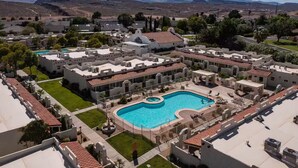 Un resort con piscina central, varias edificaciones con techos de tejas rojas y un telón de fondo montañoso.
