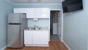 A compact kitchen with white cabinets, a stainless steel refrigerator, a granite countertop, and a ceiling fan. - Private Suite | Comfortable, Quiet & Well-Equipped (Augusta)