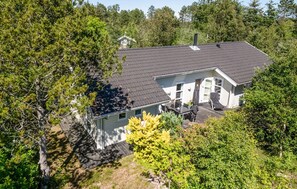Ein Haus mit dunklem Dach, weißen Außenwänden und einer Veranda mit Gartenmöbeln.