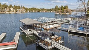 A marina with docked boats, a covered seating area, and a view of the surrounding landscape. - Serene 6-bedroom lake front house in beautiful Lake Arrowhead (Lake Arrowhead)