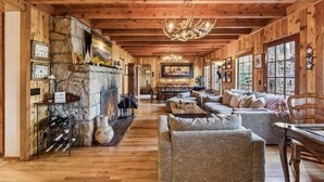 A rustic interior with a stone fireplace, wooden beams, and a cozy seating area. - Serene 6-bedroom lake front house in beautiful Lake Arrowhead (Lake Arrowhead)