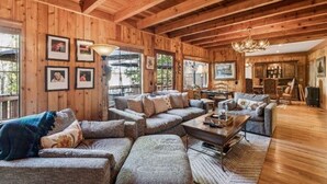 A spacious living room with wooden walls and ceiling, furnished with sofas and a coffee table. - Serene 6-bedroom lake front house in beautiful Lake Arrowhead (Lake Arrowhead)