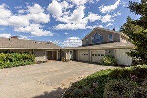 Une maison à deux étages avec un garage, une allée couverte et une pelouse bien entretenue.