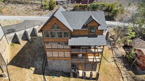 Una baita di legno a due piani con un tetto spiovente, numerose finestre e un balcone.