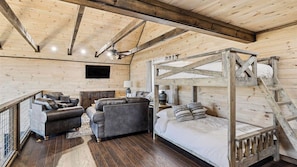 Una stanza rustica in legno con un letto a castello, divani in pelle, una TV e un pavimento in legno.