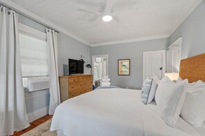 Ein Schlafzimmer mit Bett, Kommode und Deckenventilator.