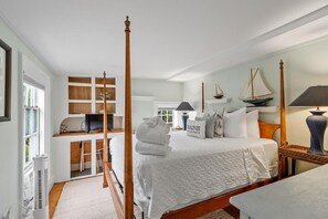 Ein Schlafzimmer mit Himmelbett, Schreibtisch mit Computer und einer Segelboot-Dekoration.