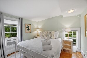 Une chambre à coucher avec un lit, des tables de chevet, une lampe et une fenêtre avec des rideaux.